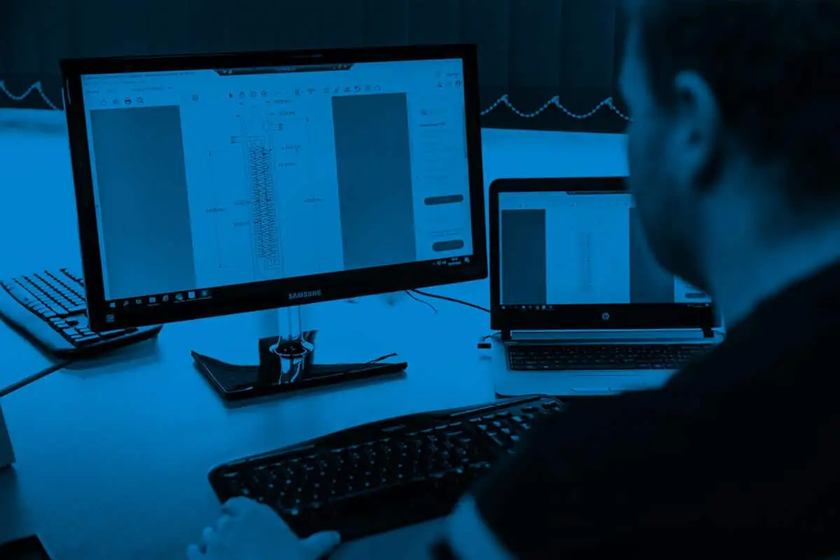 A professional working on multiple computer screens with data and analytics related to a vacuum distillation system
