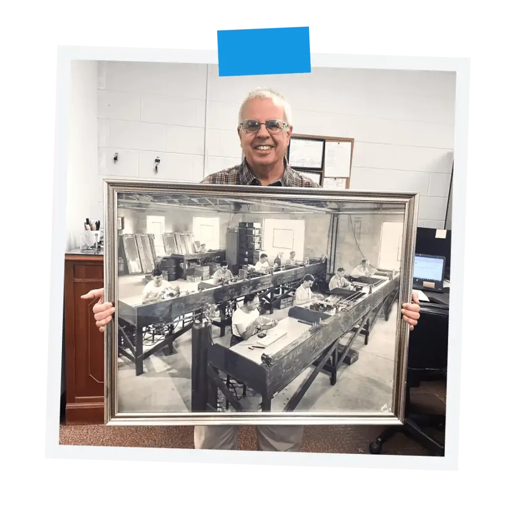 Jacketed condenser producer holding a frame black and white photograph of HS Martin factory